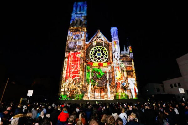 Crowds watching colourful projections on a historic Drogheda church during Lú Festival of Light
