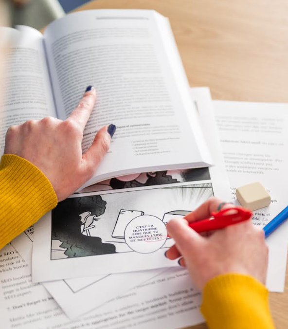 Person proofreading printed documents at a desk