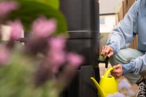 Person filling a watering can from a domestic water butt