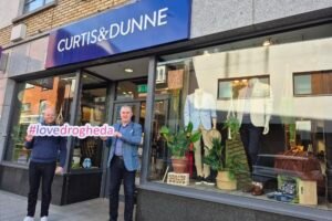 Two men outside Curtis & Dunne in Drogheda holding a Love Drogheda sign