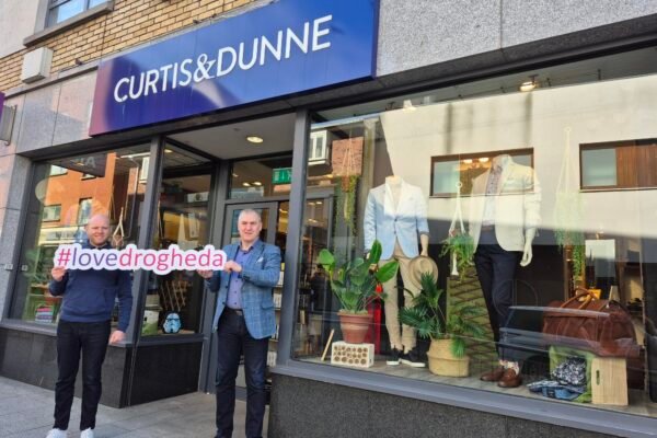 Two men outside Curtis & Dunne in Drogheda holding a Love Drogheda sign