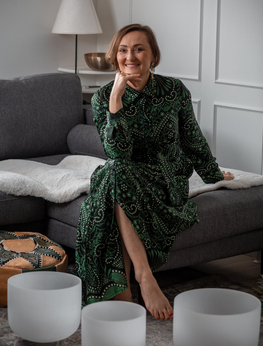 Woman seated indoors beside wellbeing bowls in a calm home setting